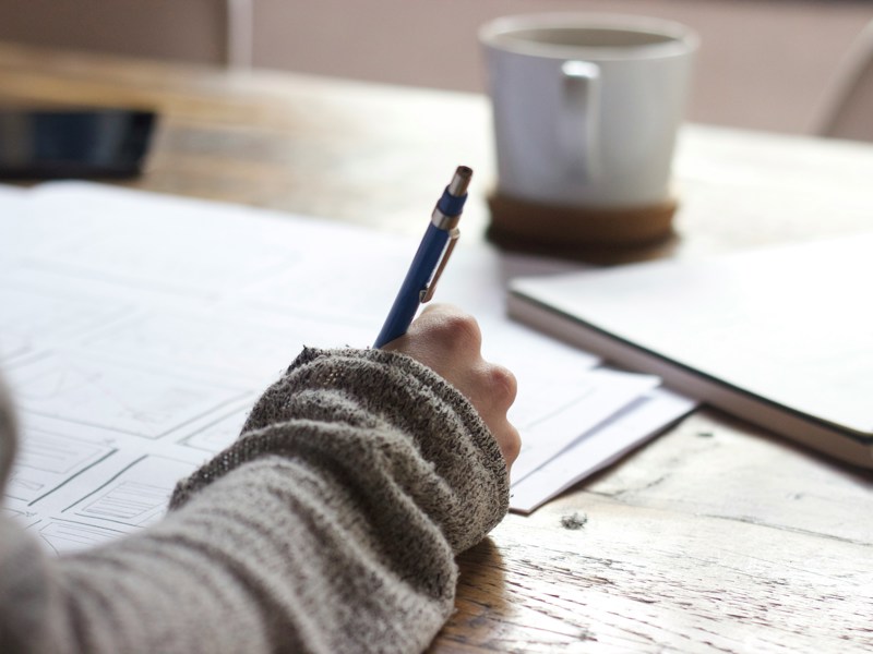 A woman holding a pen filling in forms