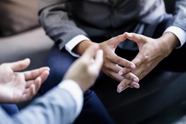 A close-up of two sets of hands engaged in a serious conversation