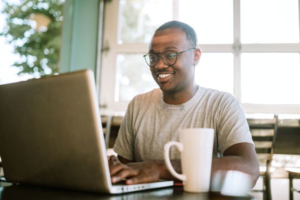 Man Working On Laptop From Cafe