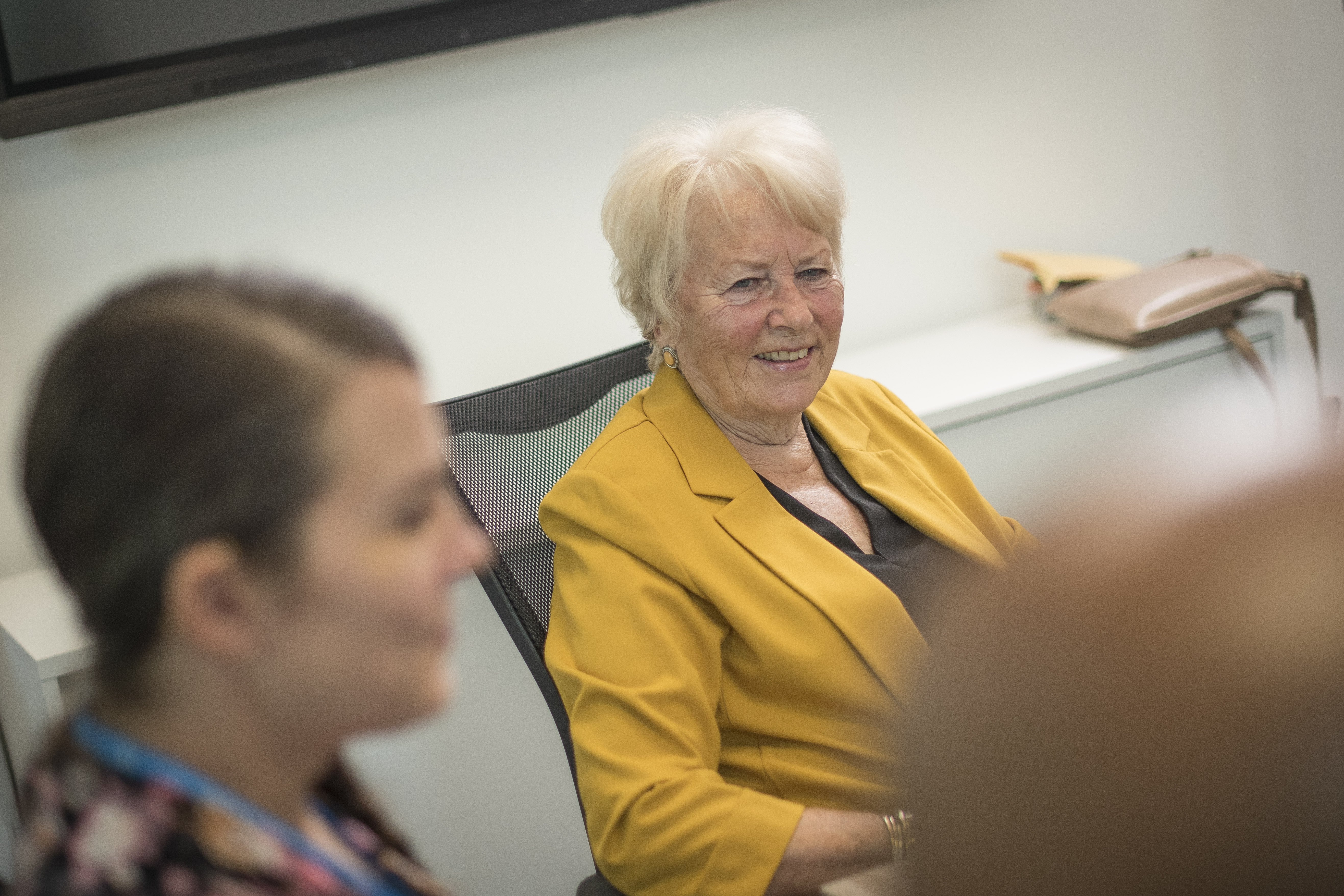 Yellow Jacket Wearing Lady In Meeting With Others