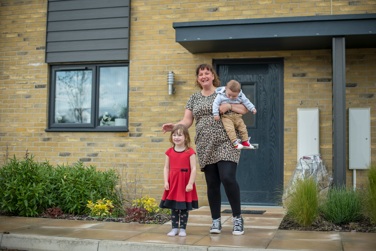 A woman and a child standing outside an Accent home smiling. She's holding a toddler in her arms 