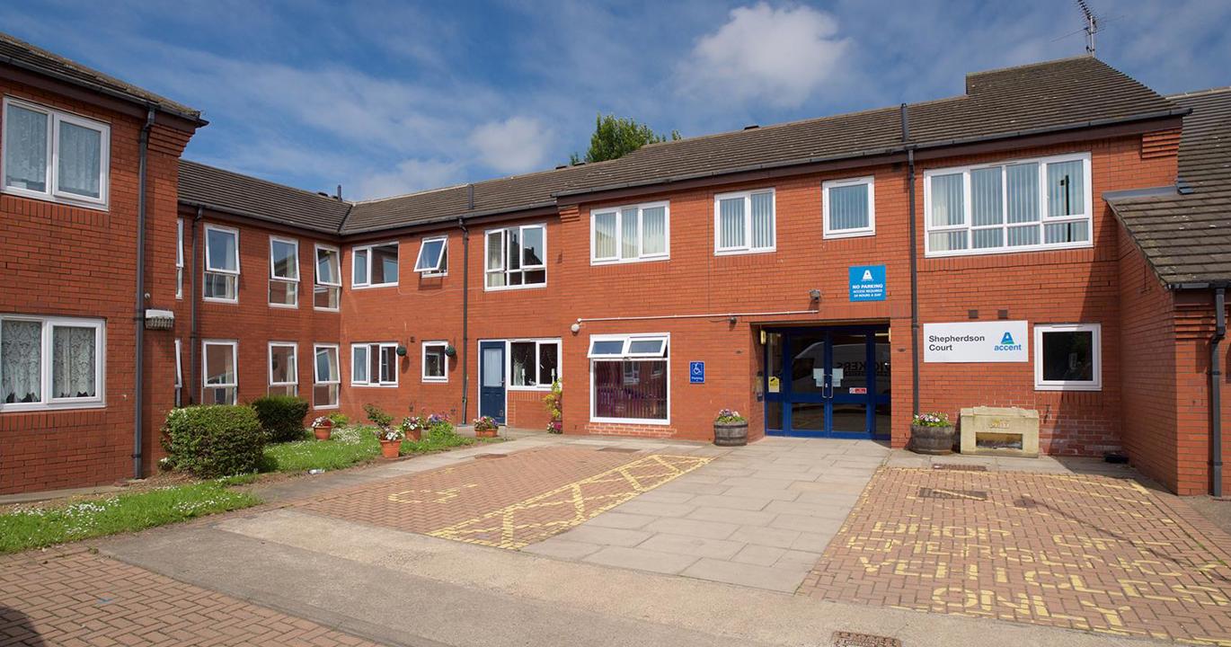 A red-brick two-storey housing development with wide driveways outside