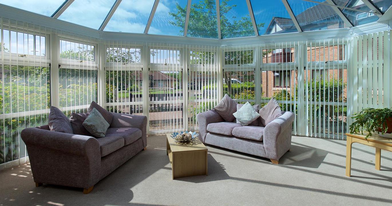 A conservatory-type room, with two sofas and a coffee table inside