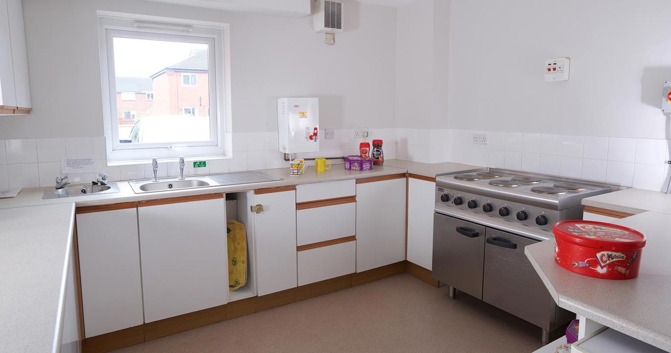 A communal kitchen with a sink, industrial-sized oven and a box of chocolates on the counter