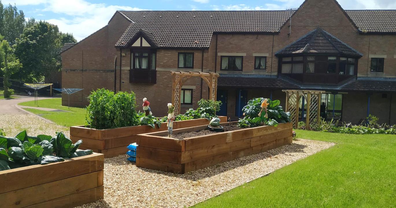 The exterior of Swan Court, a two-storey building with flower beds and a manicured lawn in the foreground