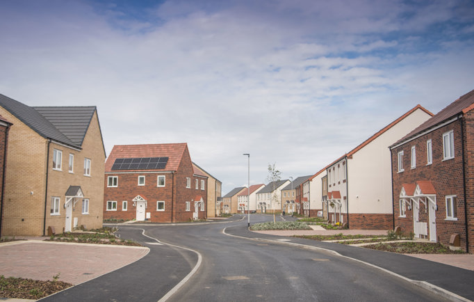 A housing development that's nearly completed, with a wide tarmac road weaving between a number of large houses