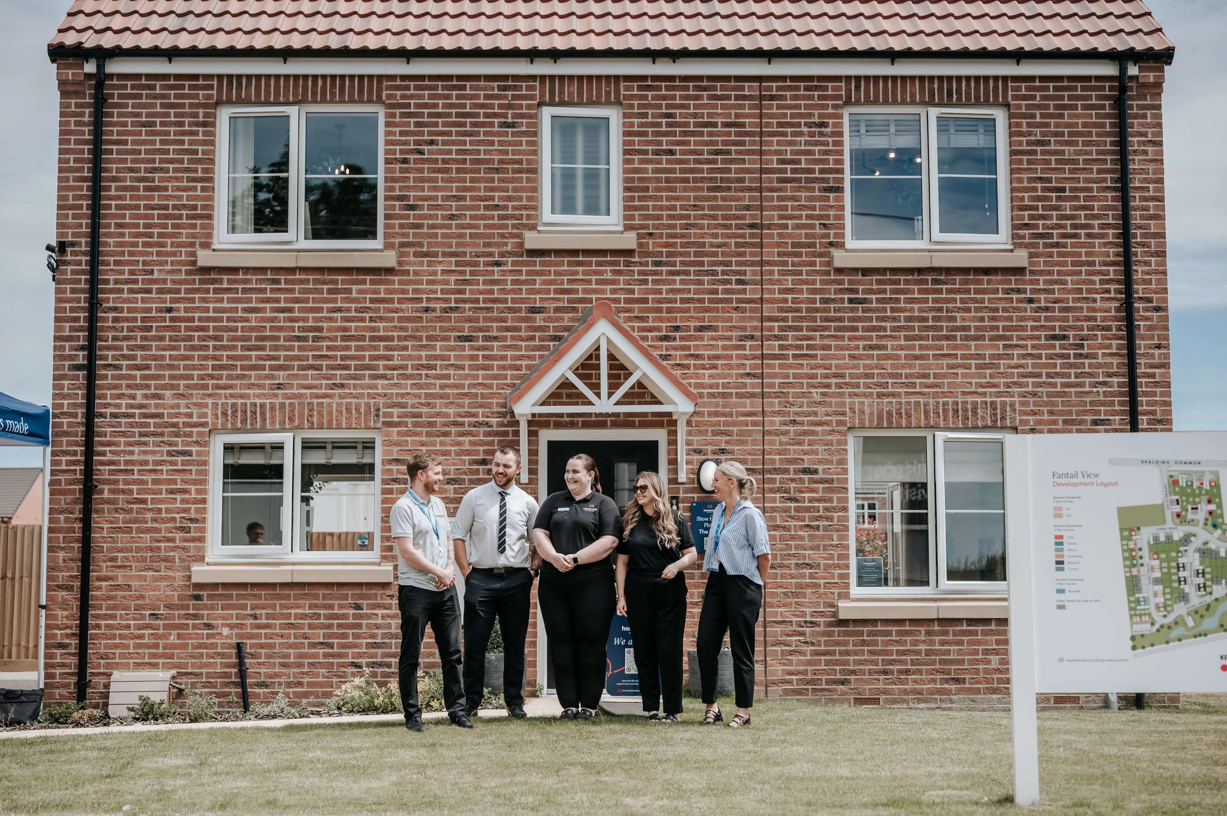 A group of Accent staff standing outside a newly built red brick property